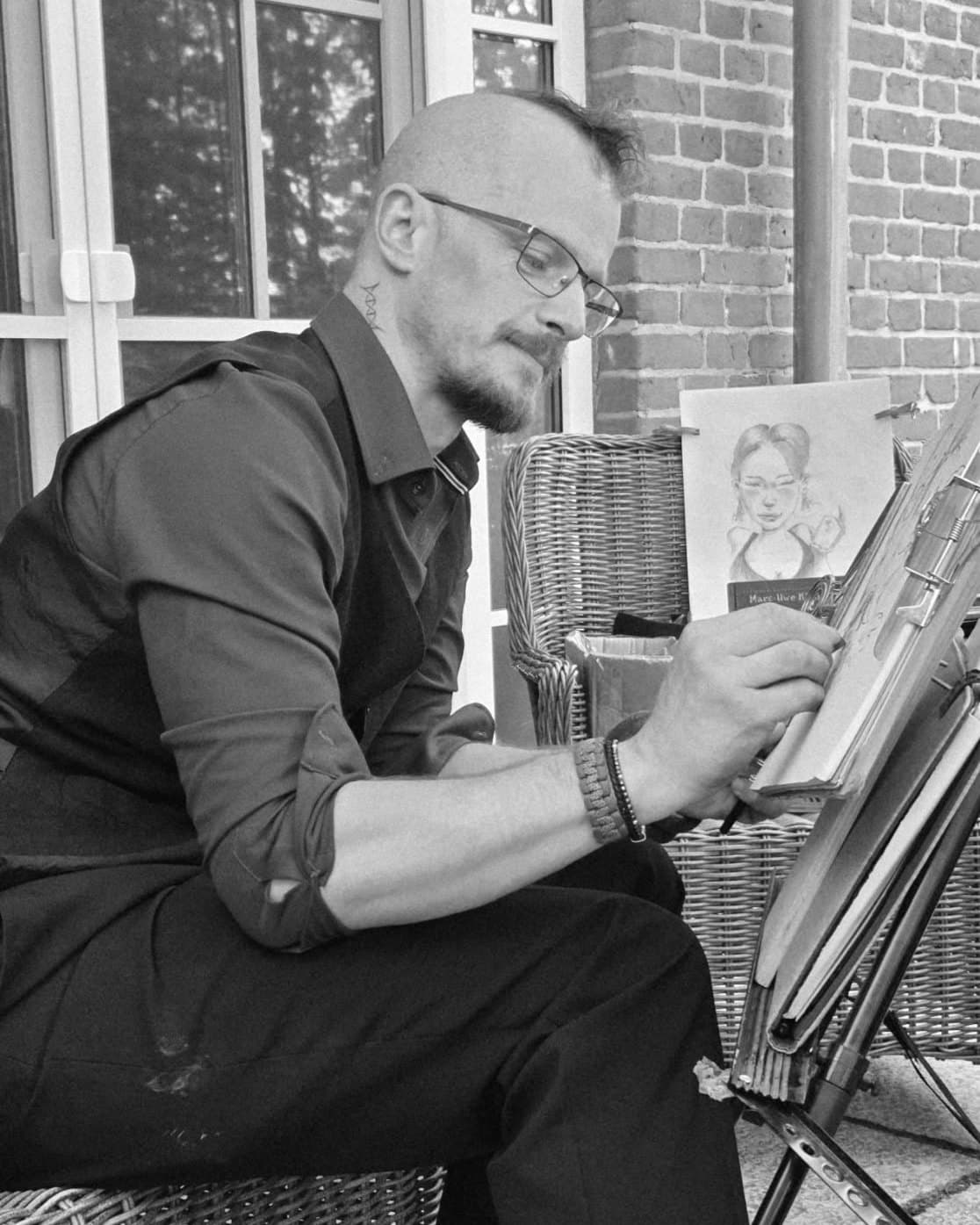 Michael Weiß an der Staffelei, den Stift am Blatt, Schwarzweißfoto